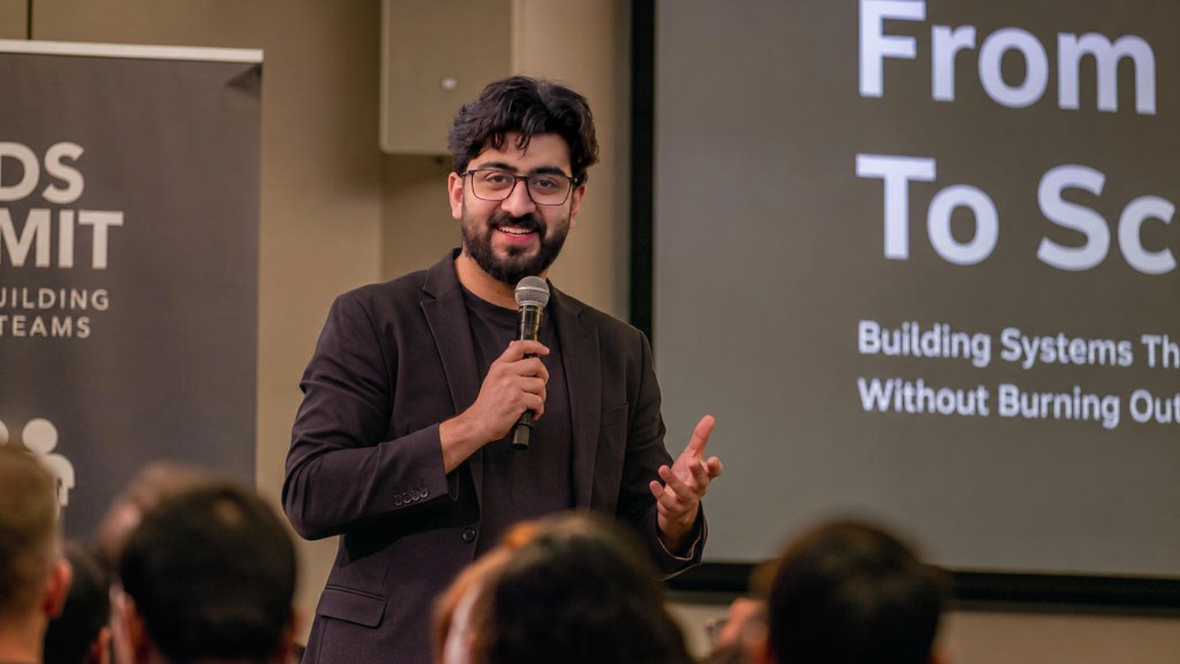 Abdullah speaking on stage at a live summit